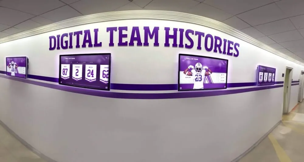 Digital displays in school hallway showing team histories